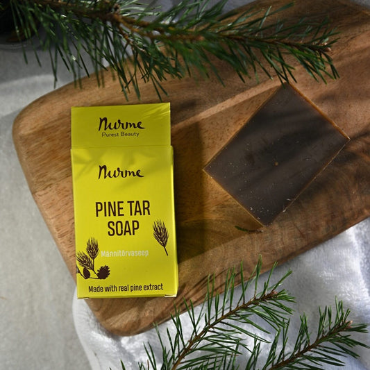 Nurme Pine Tar Soap with packaging on a wooden board with pine branches